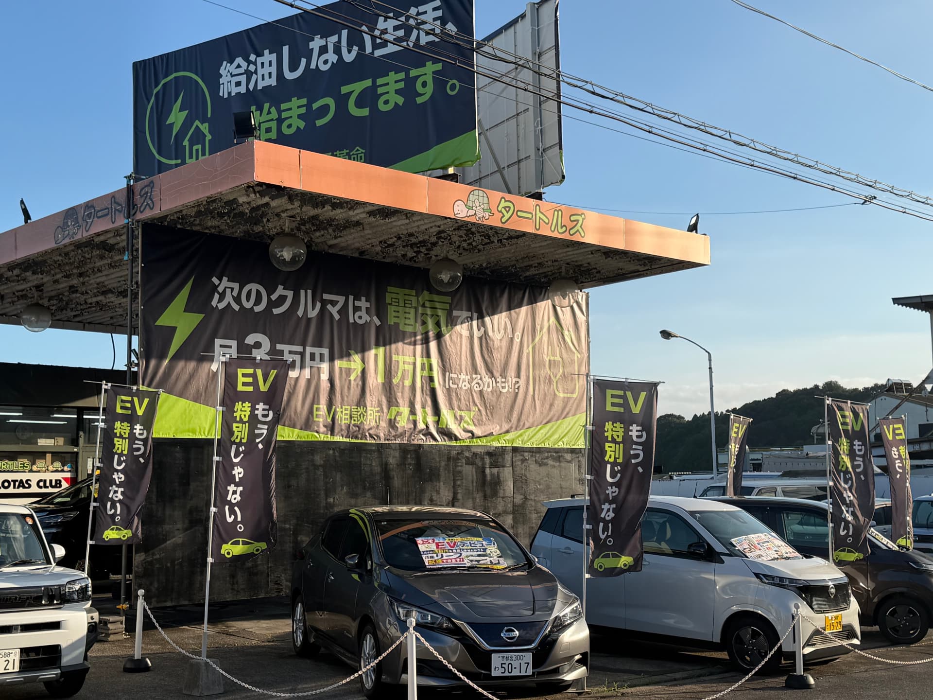斜めから見た店舗外観。EVののぼり旗が並んでいる